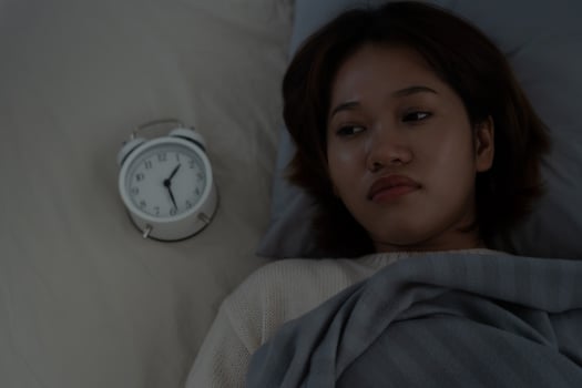 asian woman in bed late trying to sleep suffering insomnia, sleepless or scared in a nightmare, looking sad worried and stressed. Tired and headache or migraine waking up in the middle of the night. photo