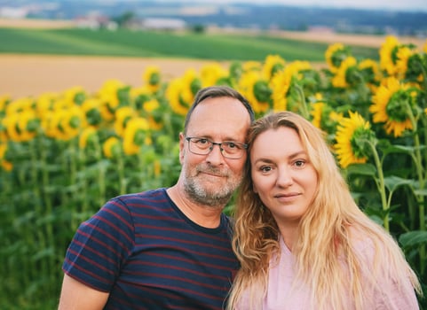 Outdoor portrait of middle age couple enjoying nice day in countryside, posing next to sunflower field photo