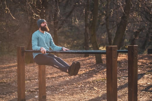 Man enjoys exercise push ups on parallel bars in the park. photo