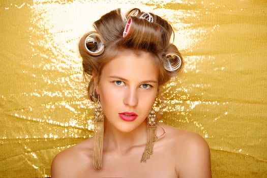 Beautiful girl in hair curlers isolated on gold photo