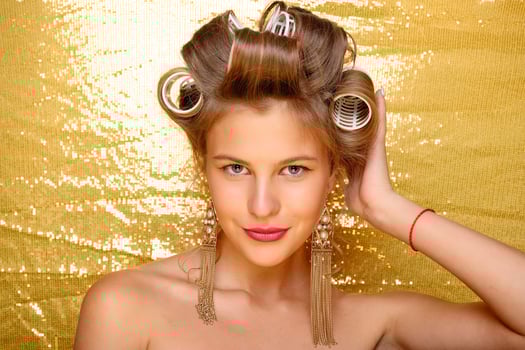 Beautiful girl in hair curlers isolated on gold photo