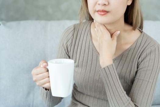 Asian woman put her hand on her neck due to a sore throat. female tonsillitis causes a inflammation. treated by taking water, taking antibiotics, consult a doctor, virus, corona virus, Influenza, flu photo