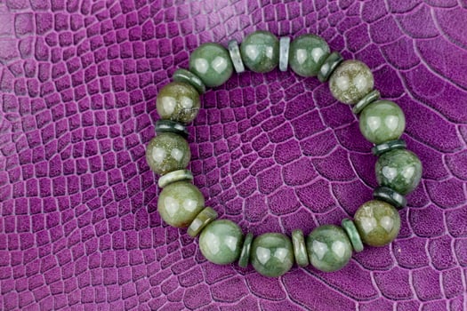 Green jade bracelet on a purple leather background. Close up. photo