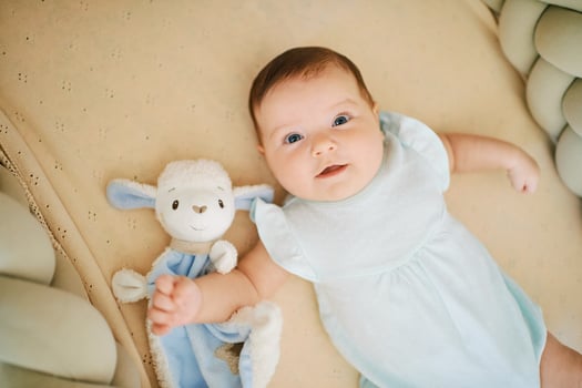 Adorable happy 6 months old baby lying in crib, play time, top view photo
