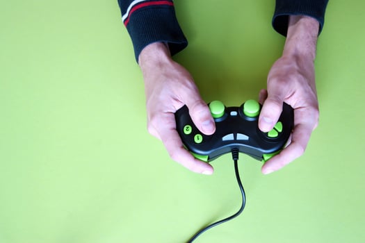Male hands hold a gamepad in light green background. photo