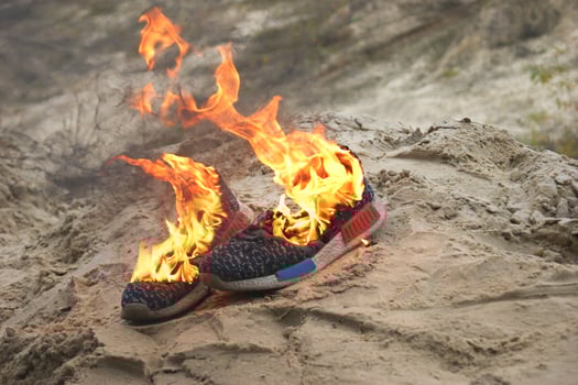 Used blue sneakers burning on a sand in the forest. photo