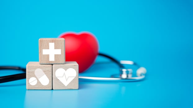 The concept of health insurance and medical welfare. Block wooden and red heart with plus icon. Health insurance and access to health care. photo