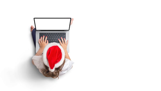 Top view of girl in Christmas hat works on laptop with isolated screen for mockup. Copy space photo
