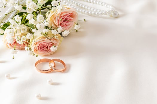 Delicate wedding arrangement with two wedding gold rings on a cream satin background with pearl beads and flowers. postcard. invitation. cover. photo