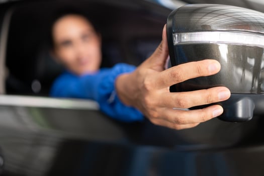 Portrait of female auto mechanic sitting behind steering wheel in a car photo