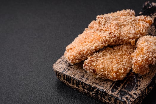 Delicious fresh crispy chicken nuggets on a dark concrete background photo