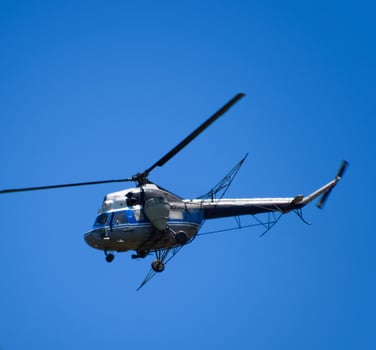 A helicopter of agricultural aviation is flying in the blue sky. photo