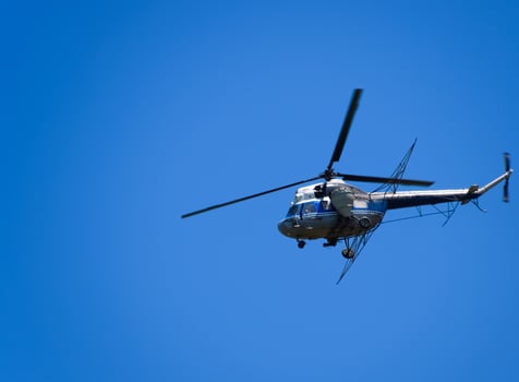 A helicopter of agricultural aviation is flying in the blue sky. photo