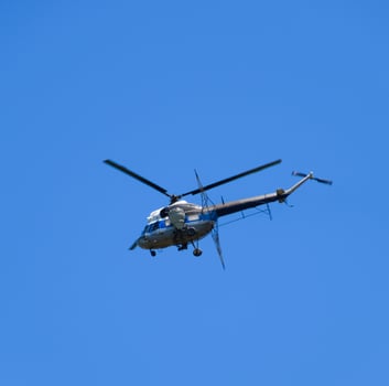 A helicopter of agricultural aviation is flying in the blue sky. photo