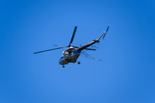A helicopter of agricultural aviation is flying in the blue sky. photo