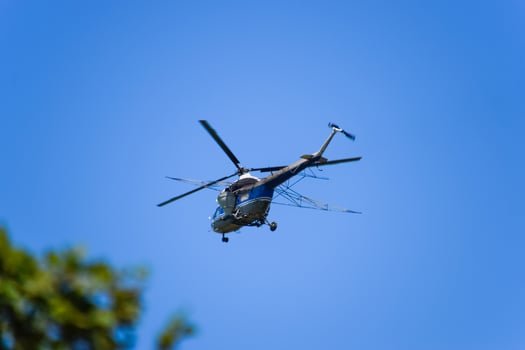A helicopter of agricultural aviation is flying in the blue sky. photo