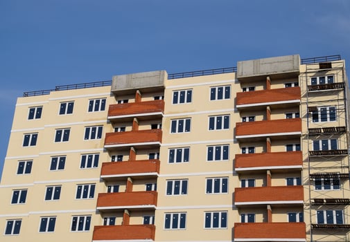 wall of a high-rise brick house, red balconies and yellow walls. photo