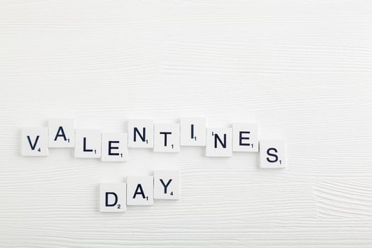 lettering valentines day on white wooden background photo