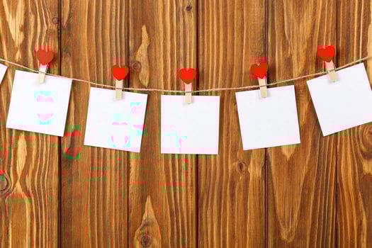 white pieces of paper on clothespins with a heart on a wooden background photo
