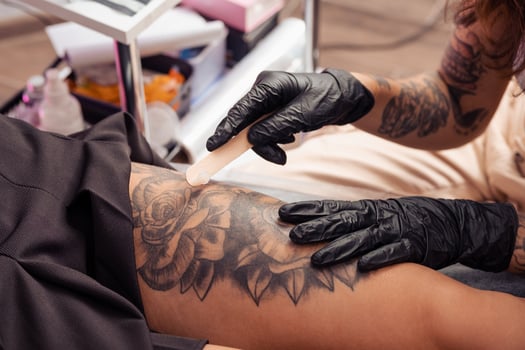 Experienced tattoo master applying healing cream on tattooed skin photo