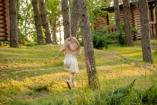 Rear view of preteen girl running in green summer city park photo