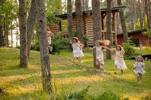Group of happy preteen girls running among trees on green lawn in country estate photo
