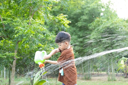 Asian boy watering plants in outdoor area photo