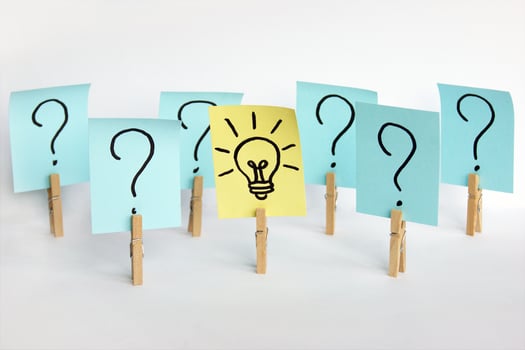 A lot of clothespins with question marks on stickers and on one light bulb, as a sign of a good idea. photo