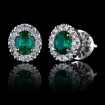 beautiful gold earrings with precious stones diamonds and emeralds on a black background photo