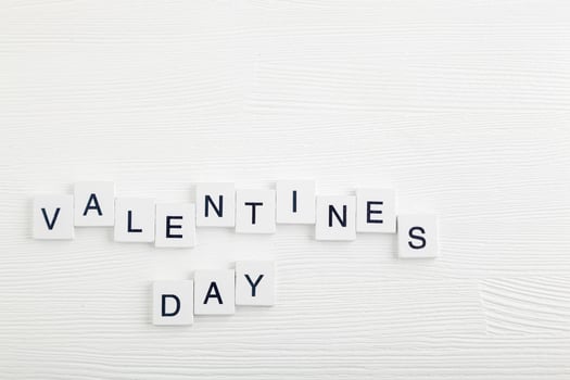 lettering valentines day on white wooden background photo