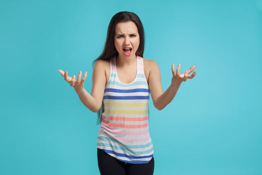 Brunette woman with long hair, dressed in striped shirt and black leggings, posing against blue studio background. Sincere emotions. Close-up. photo