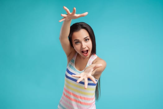 Brunette woman with long hair, dressed in colorful striped shirt, posing against blue studio background. Sincere emotions. Close-up. photo