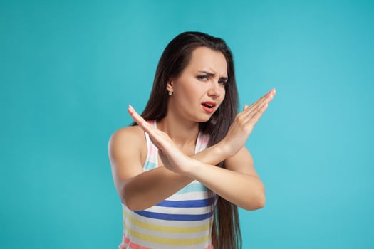 Brunette woman with long hair, dressed in colorful striped shirt, posing against blue studio background. Sincere emotions. Close-up. photo