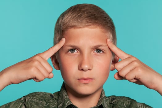 Close-up portrait of a blonde teenage boy in a green shirt with palm print posing against a blue studio background. Concept of sincere emotions. photo