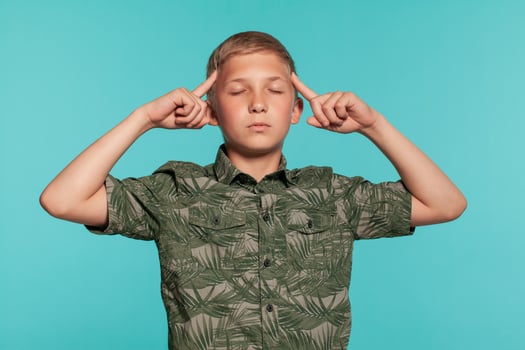 Close-up portrait of a blonde teenage boy in a green shirt with palm print posing against a blue studio background. Concept of sincere emotions. photo