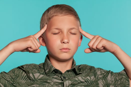 Close-up portrait of a blonde teenage boy in a green shirt with palm print posing against a blue studio background. Concept of sincere emotions. photo