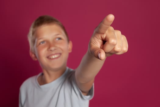 Close-up portrait of a blonde teenage boy in a white t-shirt posing against a pink studio background. Concept of sincere emotions. photo