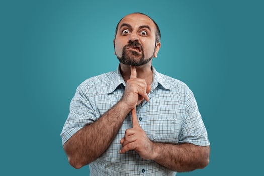 Close-up portrait of a brunet middle-aged man with beard, dressed in a light checkered shirt and posing against a blue background. photo