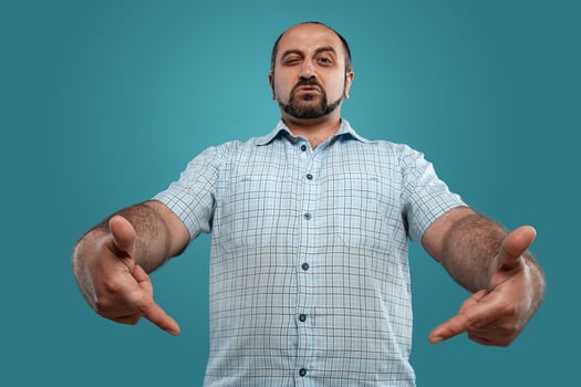 Close-up portrait of a brunet middle-aged man with beard, dressed in a light checkered shirt and posing against a blue background. photo
