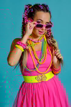 Lovely girl with a multi-colored braids hairstyle and bright make-up, posing in studio against a blue background, holding a lollipop in her hand. photo