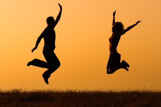 Silhouette of happy couple jumping in the nature photo