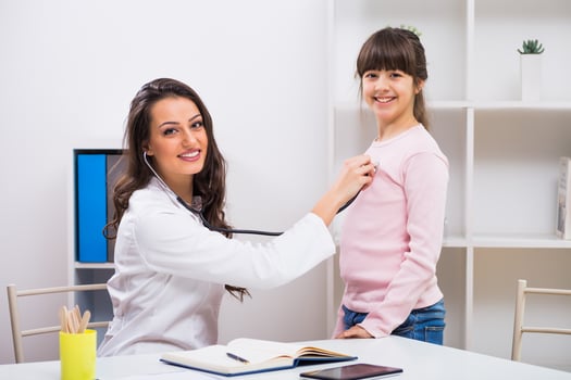 Female doctor listening heartbeat of a child with stethoscope at medical office photo
