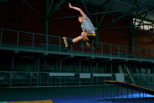 Rollerblader jump high from big air ramp performing trick. Indoors skate park equipment. photo