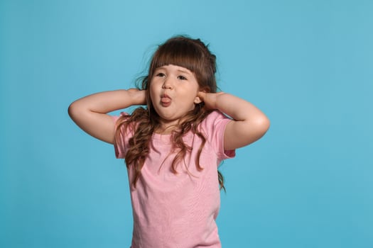 Beautiful little girl wearing in a pink t-shirt is posing against a blue studio background. photo