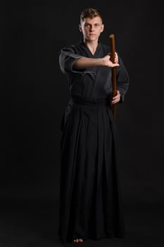 Kendo guru wearing in a traditional japanese kimono is practicing martial art with the shinai bamboo sword against a black studio background. photo