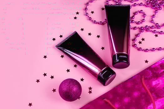 Black and pink cosmetic tubes on pastel background. Squeeze bottles and purple christmas decorations photo