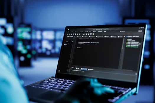 Certified technician running code and programming on laptop, troubleshooting and upgrading high tech facility designed to accommodate multiple rows of fully operational server rigs, close up photo