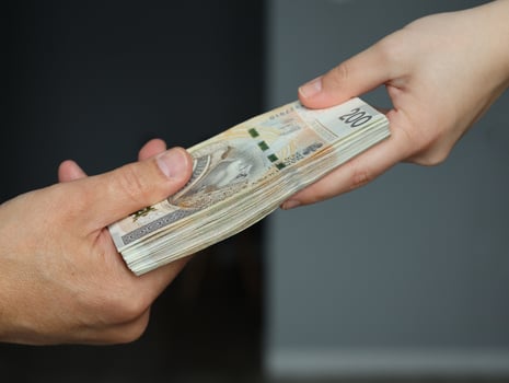 male hand giving a bundle of large banknotes to female hands. selective focus photo