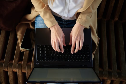 Woman sitting on bench and typing on laptop keyboard photo