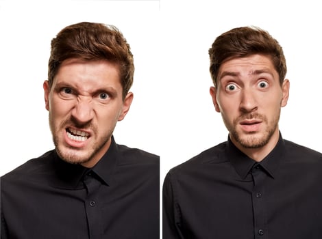 Handsome man in a black shirt makes faces, standing against a white background photo